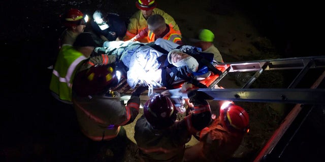 In this photo provided by the Iron County Sheriff's Department, emergency personnel remove an injured train worker from the scene of a train derailment near Lund, Utah, Thursday, July 15, 2021. Three employees of a goods train were injured when it derailed while crossing. A water-covered track in a remote part of southern Utah on Thursday night, officials said. The train, which had about 100 cars, turned on its side after derailing near Lund, about 85 miles from the Nevada border. (Iron County Sheriff's Department via AP)