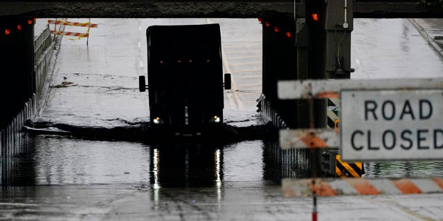 A semi-trailer travels through a flooded road on Friday, July 16, 2021 in Dearborn, Mich. Detroit area residents are still drying out their basements from last month's flooding, but now more flooding is on the horizon as heavy rain moves through southern Michigan. (AP Photo/Carlos Osorio)