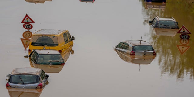 Cars show up as the flood sinks on a road in Erftstadt, Germany, Saturday, July 17, 2021. Due to strong rain falls the small Erft river went over the banks causing massive damages. (AP Photo/Michael Probst)