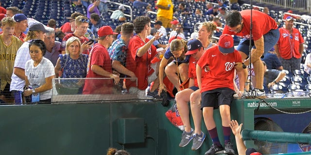 Fans jump into a camera well after hearing gunfire from outside Nationals Park during a Saturday baseball game between the San Diego Padres and the Washington Nationals. (John McDonnell/The Washington Post via AP)