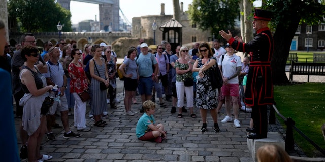 On what some have called "Freedom Day", marking the end of coronavirus restrictions in England, visitors listen as Yeoman Warder Barney Chandler leading the first tour of the Tower of London in 16 months since the start of the coronavirus outbreak, in London, Monday, July 19, 2021. Beginning Monday, face masks will no longer be legally required and with social distancing rules shelved, but mask rules will remain for passengers on the London transport network.  (AP Photo/Matt Dunham)