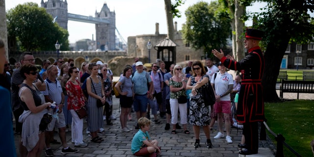 On what some have called "Freedom Day", marking the end of coronavirus restrictions in England, visitors listen as Yeoman Warder Barney Chandler leading the first tour of the Tower of London in 16 months since the start of the coronavirus outbreak, in London, Monday, July 19, 2021. Beginning Monday, face masks will no longer be legally required and with social distancing rules shelved, but mask rules will remain for passengers on the London transport network. (AP Photo/Matt Dunham)