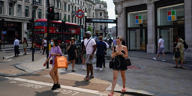 People walk in Oxford Circus, in London, Monday, July 19, 2021. As of Monday, face masks are no longer legally required in England, and with social distancing rules shelved, there are no limits on the number of people attending theater performances or big events. (AP Photo/Alberto Pezzali)