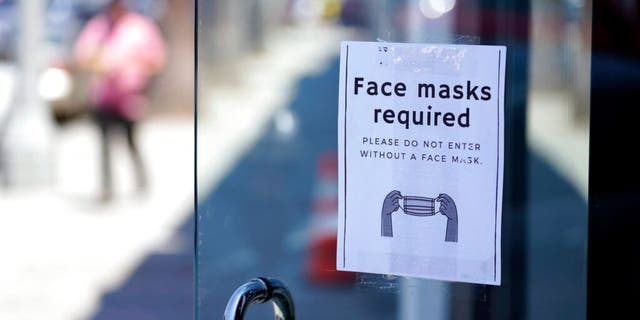 A sign advises shoppers to wear masks outside of a story Monday, July 19, 2021, in the Fairfax district of Los Angeles.  (AP Photo/Marcio Jose Sanchez)