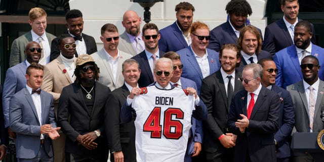 President Joe Biden, surrounded by members of the Tampa Bay Buccaneers, poses for a photo holding a jersey during a ceremony on the South Lawn of the White House, in Washington, Tuesday, July 20, 2021(AP Photo/Andrew Harnik)