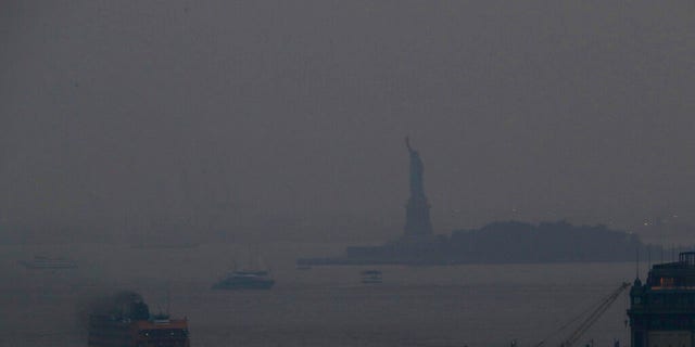 The Staten Island Ferry departs from the Manhattan terminal through a haze of smoke with the Statue of Liberty barely visible, Tuesday, July 20, 2021, in New York.