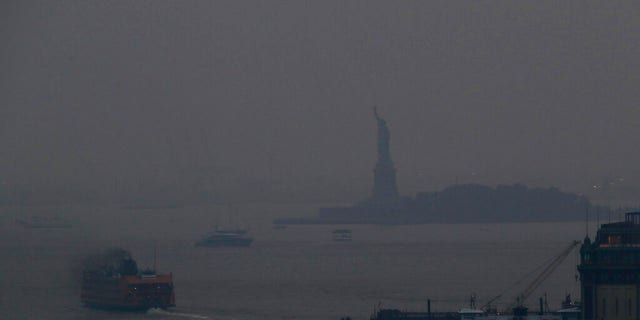The Staten Island Ferry departs from the Manhattan terminal through a haze of smoke with the Statue of Liberty barely visible, Tuesday, July 20, 2021, in New York.