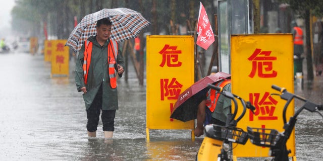 In this photo released by Xinhua News Agency, staff members set up warning signs with the words "Danger!" at a waterlogged area in Wuzhi County in central China's Henan Province on Tuesday, July 20, 2021. At least a dozen people died in severe flooding Tuesday in a Chinese provincial capital that trapped people in subways and schools, washed away vehicles and stranded people in their workplaces overnight. (Feng Xiaomin/Xinhua via AP)