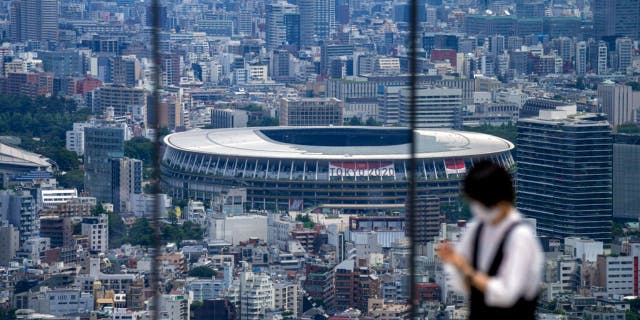 A person takes a picture from an observation deck as National Stadium, where the opening ceremony of the Tokyo Olympics will be held, is seen in the background in Tokyo.