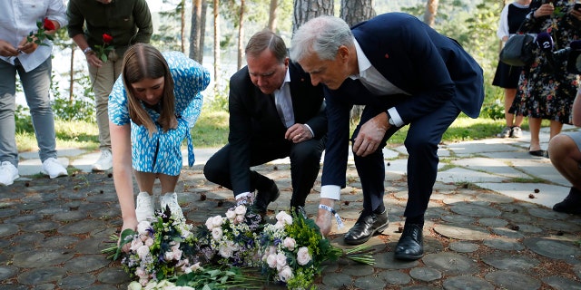 Leader of AUF youth political league in Norway, Astrid Hoem, Prime Minister of Sweden Stefan Lofven and leader of the Norwegian Labor Party Jonas Gahr Store, lay flower tributes at the memorial on Utoya island Wednesday, July 21, 2021. (Beate Oma Dahle / NTB via AP)