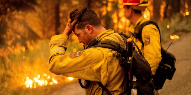 Firefighter Jesse Forbes rubs his head while battling the Dixie Fire near Prattville in Plumas County, Calif., on Friday, July 23, 2021. (AP Photo/Noah Berger)