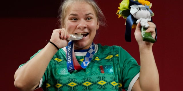 Polina Guryeva of Turkmekistan celebrates on the podium after winning the silver medal in the women's 59kg weightlifting event, at the 2020 Summer Olympics, Tuesday, July 27, 2021, in Tokyo, Japan. She won gold medal and sets a new Olympic record. (AP Photo/Luca Bruno)