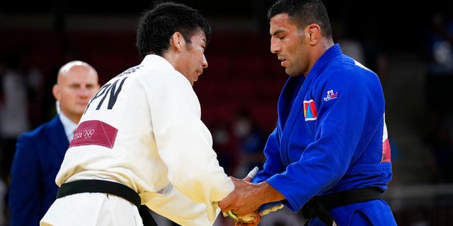 Takanori Nagase of Japan, at left shakes hand with Saeid Mollaei of Mongolia after defeating him to win the men -81kg final of the judo match at the 2020 Summer Olympics in Tokyo, Japan, Tuesday, July 27, 2021. (AP Photo/Vincent Thian)