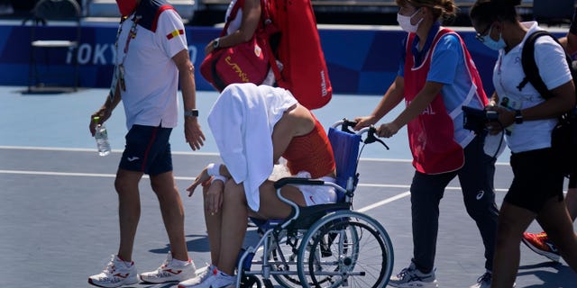 Paula Padusa, Spain, is helped off the court in a wheelchair following withdrawing due to illness during the quarter-finals of the tennis competition at the 2020 Summer Olympics, Wednesday, July 28, 2021, in Tokyo, Japan. (AP Photo / Seth Wenig)