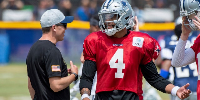 Dallas Cowboys quarterback Dak Prescott (4) talks with offensive coordinator Kellen Moore, left, during practice at the NFL football team's training camp in Oxnard, Calif., Wednesday, July 28, 2021. (AP Photo/Michael Owen Baker)