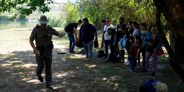 Texas Department of Public Safety officers work with a group of migrants who have crossed the border and made their way to Del Rio, Texas. 