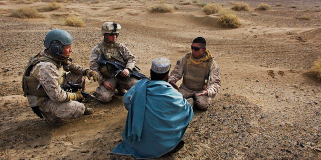 In this Friday, Dec. 11, 2009, file photo, United States Marine Sgt. Isaac Tate, left, and Cpl. Aleksander Aleksandrov, center, interview a local Afghan man with the help of a translator from the 2nd MEB, 4th Light Armored Reconnaissance Battalion on a patrol in the volatile Helmand province of southern Afghanistan. More than 200 Afghans were due to land Friday in the United States in the first of several planned evacuation flights for former translators and others as the U.S. ends its nearly 20-year war in Afghanistan. (AP Photo/Kevin Frayer, File)
