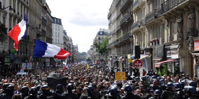 Protestors march waving French flags during a demonstration in Paris, France, Saturday, July 31, 2021. Demonstrators gathered in several cities in France on Saturday to protest against the COVID-19 pass, which grants vaccinated individuals greater ease of access to venues.