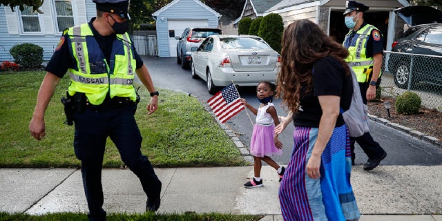 FILE - This photo from Monday July 13, 2020, shows Nassau County Police officers walk alongside protesters participating in a Black Lives Matter march through a residential neighborhood calling for racial justice in Valley Stream, N.Y.