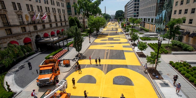 People walk down 16th street after volunteers, with permission from the city, painted "Black Lives Matter" on the street near the White House on June 05, 2020 in Washington, DC. 