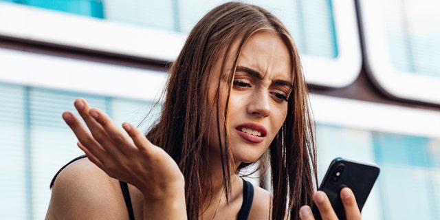 Woman looking at phone while frustrated