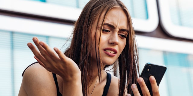 Woman looking at phone while frustrated
