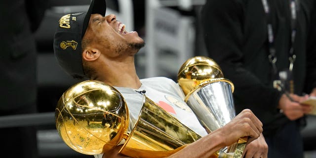 Milwaukee Bucks forward Giannis Antetokounmpo reacts while holding the NBA Championship trophy, left, and Most Valuable Player trophy after defeating the Phoenix Suns in Game 6 of basketball's NBA Finals in Milwaukee, Tuesday, July 20, 2021. The Bucks won 105-98.