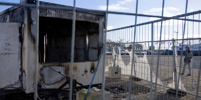 A person walks past a burned-out coronavirus testing facility in the fishing village of Urk in the Netherlands on Jan. 24 after it was set on fire the night before by rioting youths protesting on the first night of a nationwide curfew.