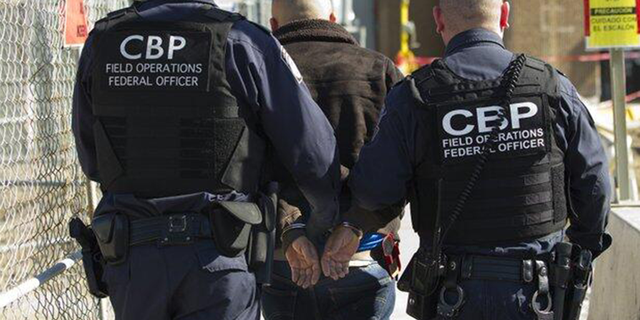 CBP officers escort a wanted person at a U.S. port of entry.