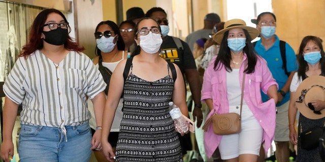 In this July 1, 2021, file photo, visitors wear masks as they walk in a shopping district in the Hollywood section of Los Angeles.
