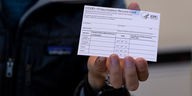 Sarah Gonzalez of New York, a Nurse Practitioner, displays a COVID-19 vaccine card at a New York Health and Hospitals vaccine clinic in the Brooklyn borough of New York.