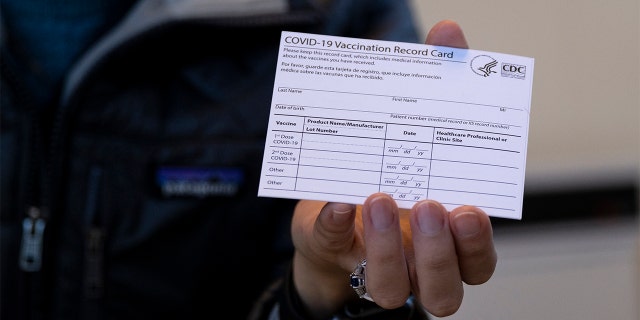 Sarah Gonzalez of New York, a Nurse Practitioner, displays a COVID-19 vaccine card at a New York Health and Hospitals vaccine clinic in the Brooklyn borough of New York.