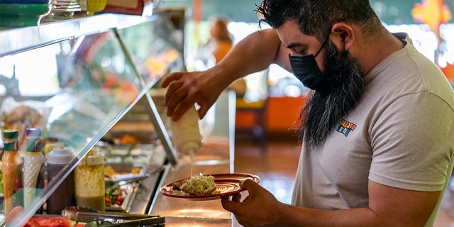 Gustavo Arellano, 36, who is vaccinated, wears a face mask as he fixes himself a plate at Taqueria El Sol buffet in Los Angeles' Boyle Heights neighborhood in Los Angeles, Thursday, July 22, 2021. 