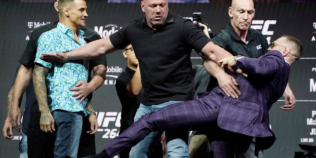 Conor McGregor, right, kicks at Dustin Poirier, left, as Dana White, UFC President, holds them apart during a news conference for a UFC 264 mixed martial arts bout Thursday, July 8, 2021, in Las Vegas. (AP Photo/John Locher)