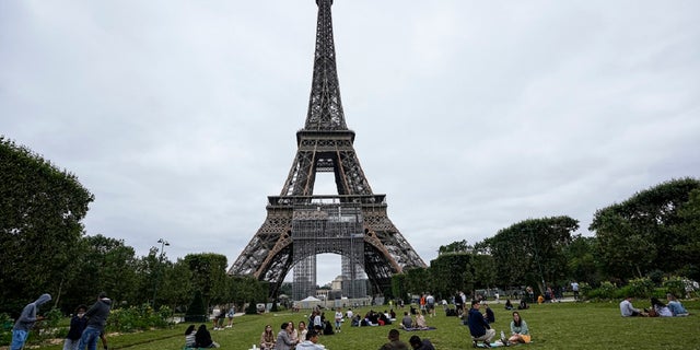 People relax at the Champ-de-Mars garden next to the Eiffel Tower in Paris, Friday, July 16, 2021. 