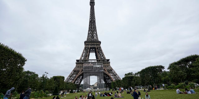 People relax at the Champ-de-Mars garden next to the Eiffel Tower in Paris, Friday, July 16, 2021. 