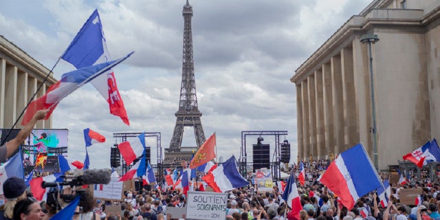 Thousands of protesters gather at Place Trocadero near the Eiffel Tower attend a demonstration in Paris, France, Saturday July 24, 2021, against the COVID-19 pass which grants vaccinated individuals greater ease of access to venues.