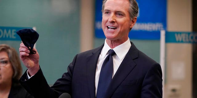 California Gov. Gavin Newsom holds a face mask while speaking at a news conference in Oakland, Calif., Monday, July 26, 2021.