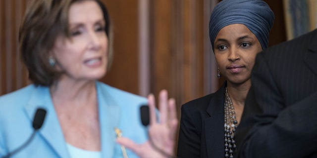 Representative Ilhan Omar, a Democrat from Minnesota, listens as U.S. House Speaker Nancy Pelosi, a Democrat from California, left, speaks during a bill enrollment ceremony for the Juneteenth National Independence Day Act at the U.S. Capitol in Washington, D.C., U.S., on Thursday, June 17, 2021. The legislation, passed by the House and Senate earlier this week, would make June 19 a federal holiday commemorating the end of slavery in the U.S. Photographer: Sarah Silbiger/Bloomberg via Getty Images