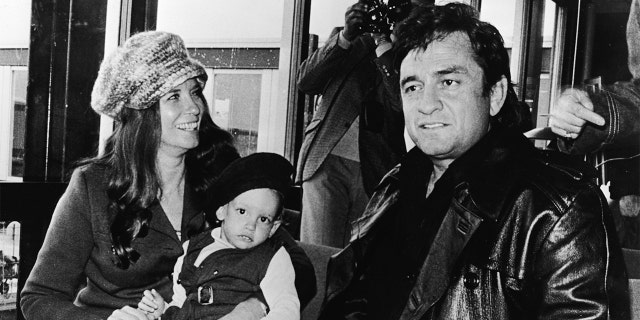American country singer Johnny Cash (1932 - 2003) sits inside an airport with his wife June Carter Cash (1929 - 2003) and their infant son John Carter Cash, as the singer arrived in Copenhagen, Denmark to begin his Scandinavian tour, circa 1971.
