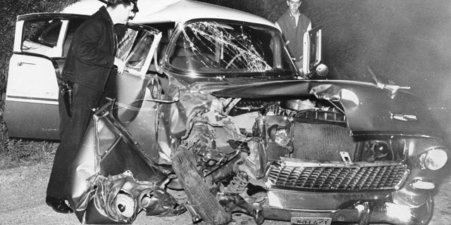 A policeman examines the wreckage of actor Montgomery Clift's car after it crashed into a power pole following a dinner party at the home of Michael Wilding and Elizabeth Taylor. Clift suffered serious head injuries.