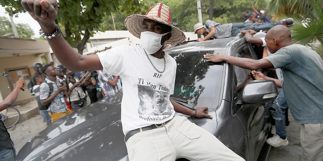 Supporters of former Senator Steven Benoit shout outside the courthouse as he departs after being called in for questioning, in Port-au-Prince, Monday, July 12, 2021. Prosecutors have requested that high-profile politicians like Benoit meet officials for questioning as part of the investigation into the assassination of President Jovenel Moise. (AP Photo/Fernando Llano)