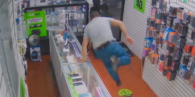A Queens cellphone store employee jumped over the counter to stop a trio of crooks — and ended up getting robbed himself, according to cops and surveillance video.