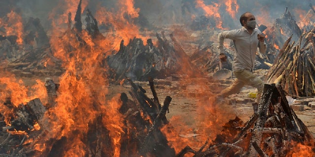 A man runs to escape the heat emitted by the multiple funeral pyres of COVID-19 victims at a crematorium on the outskirts of New Delhi, India on April 29.