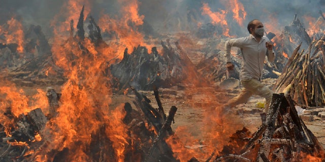 A man runs to escape the heat emitted by the multiple funeral pyres of COVID-19 victims at a crematorium on the outskirts of New Delhi, India on April 29.