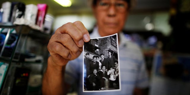 파일 사진 : Resident Kohei Jinno, 79, shows a photograph of himself (2nd L wearing suit) taken on January 2, 1957 in front of his previous home, at his shop inside Kasumigaoka apartment complex which is located near the National Olympic Stadium in Tokyo September 18, 2013.