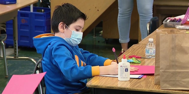 A child is shown wearing a mask indoors while working on a school project in this file photo.