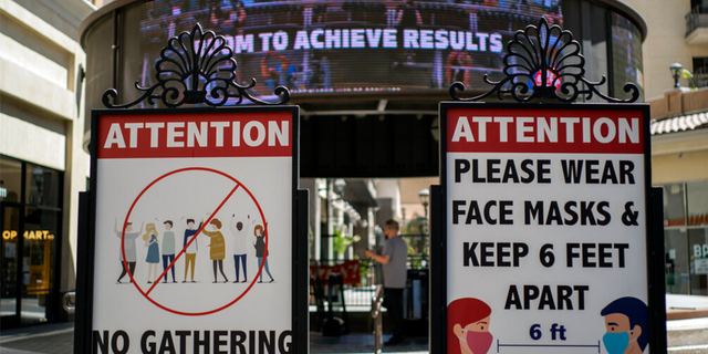 FILE: Signs with social distancing guidelines and face mask requirements are posted at an outdoor mall amid the COVID-19 pandemic in Los Angeles. 