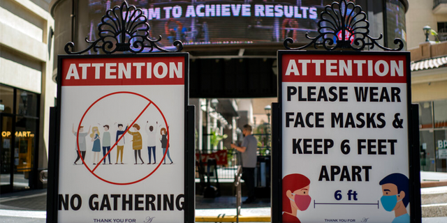 FILE: Signs with social distancing guidelines and face mask requirements are posted at an outdoor mall amid the COVID-19 pandemic in Los Angeles.
