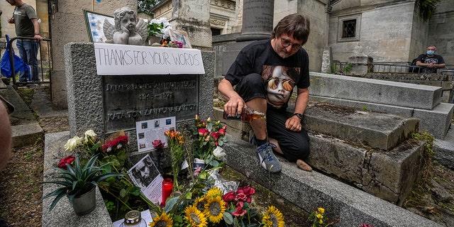 Torsten Marquardt of Germany pours some whiskey on the grave of rock singer Jim Morrison at the Pere-Lachaise Cemetery in Paris, Saturday, July 3, 2021. (Associated Press)